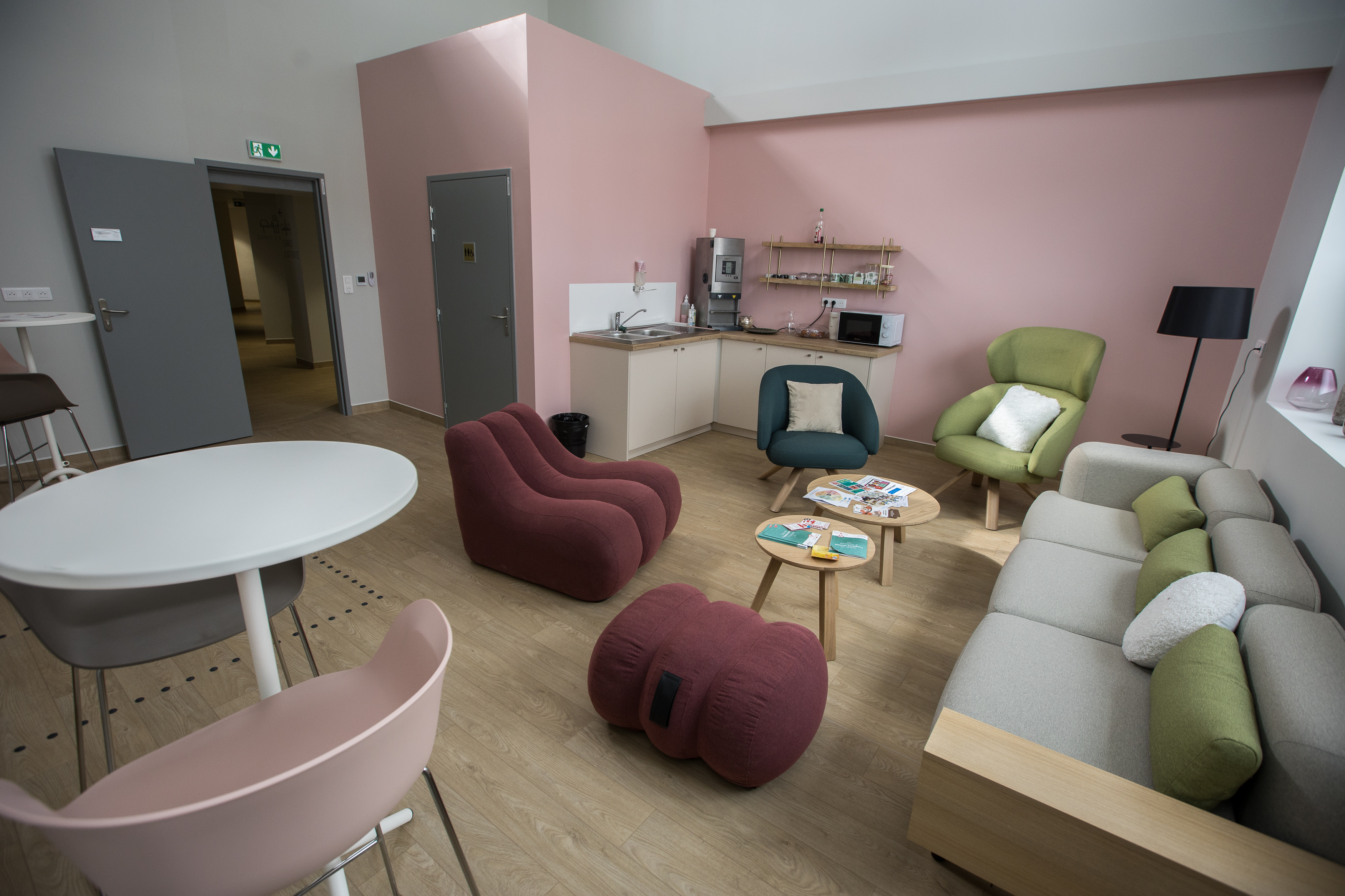 Salon d'accueil avec fauteuils, canapé, machine à café, mange debout, toilettes