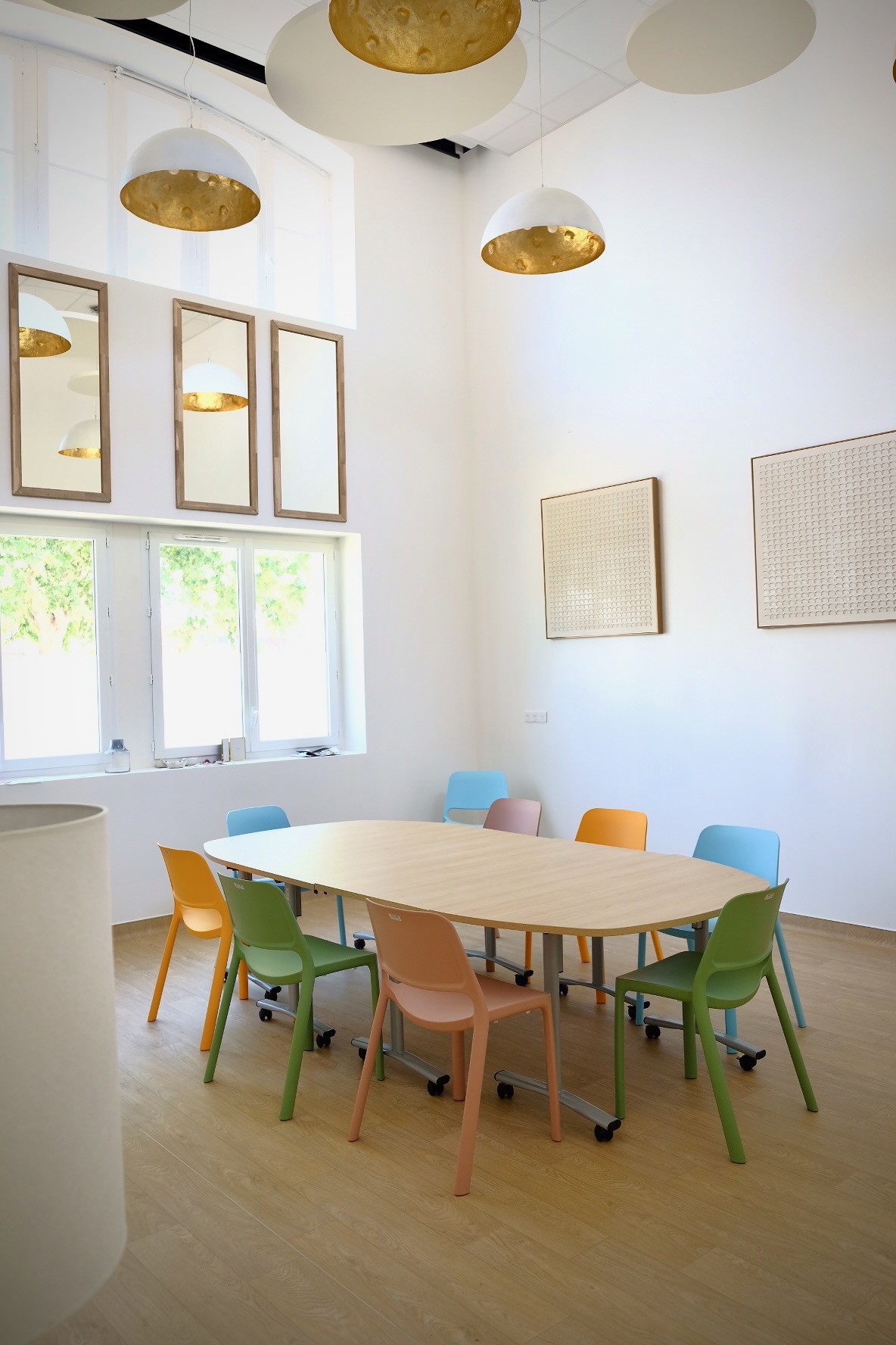 Grande pièce avec table de réunion au centre et chaises, miroirs au mur